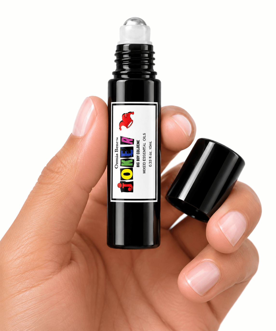 A hand holding an open Omnia Bene JOKER boys rollerball cologne with the cap alongside.