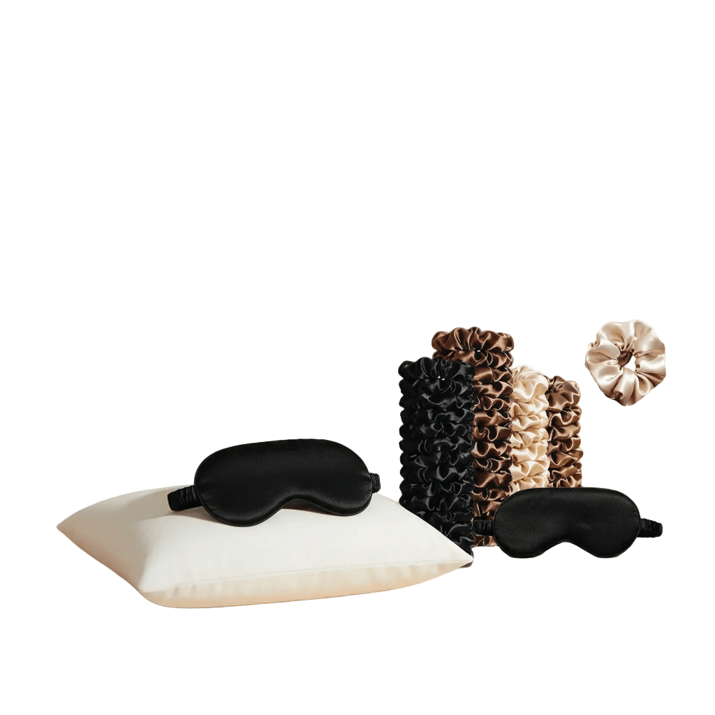 Omnia Bene satin beauty eye masks and satin hair ties in black, brown, champagne and gold on a pillow.