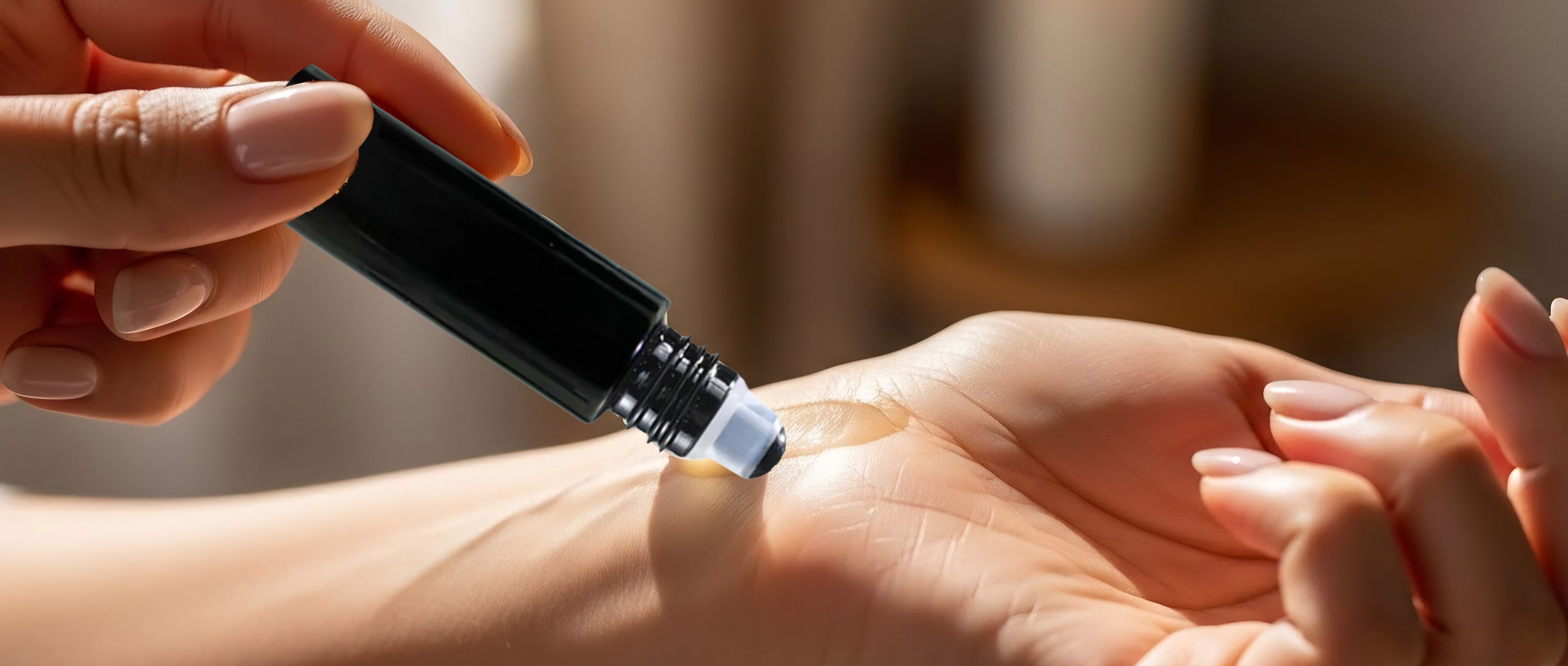 Person applying rollerball essential oil with hand to wrist with gradient background