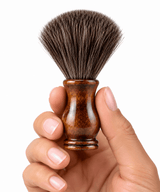 A hand holding the Omnia Bene Heritage shave brush with its dense knot and polished wood handle.