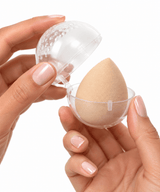 Hands opening a clear protective case from the Omnia Bene makeup sponges set, holding a nude sponge.