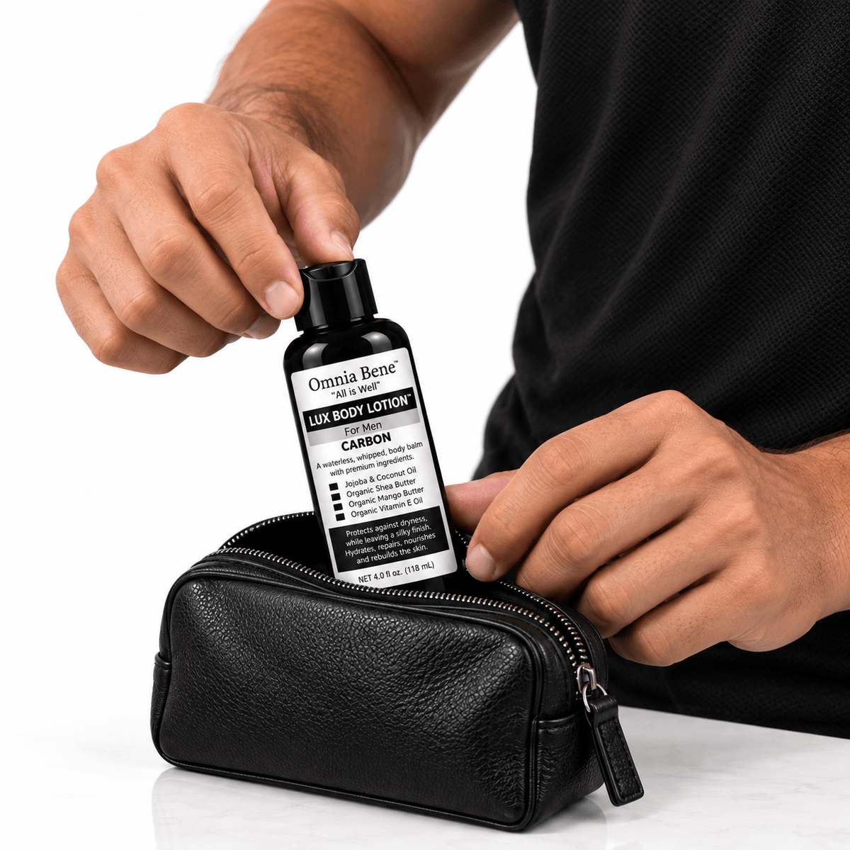 A man placing Omnia Bene Carbon Body Lotion into a black leather toiletry case.