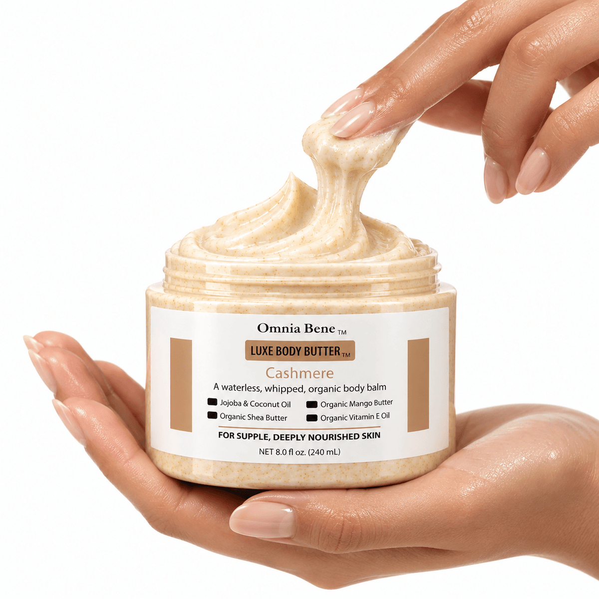 Hands holding an open jar of Omnia Bene Organic Luxury Body Butter — close-up of the whipped waterless texture with jojoba, coconut and vitamin E