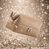 Omnia Bene Puccian Italian leather travel case in tan against a backdrop of sparkling crystals.