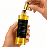 Hands lifting the gold cap from a bottle of Omnia Bene Puccian Liquid Gold luxury body oil.