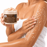 Omnia Bene RESTORE Body Scrub held beside an arm coated in the sugar and salt polish.
