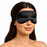 A woman wearing an Omnia Bene black satin eye mask for restful sleep.